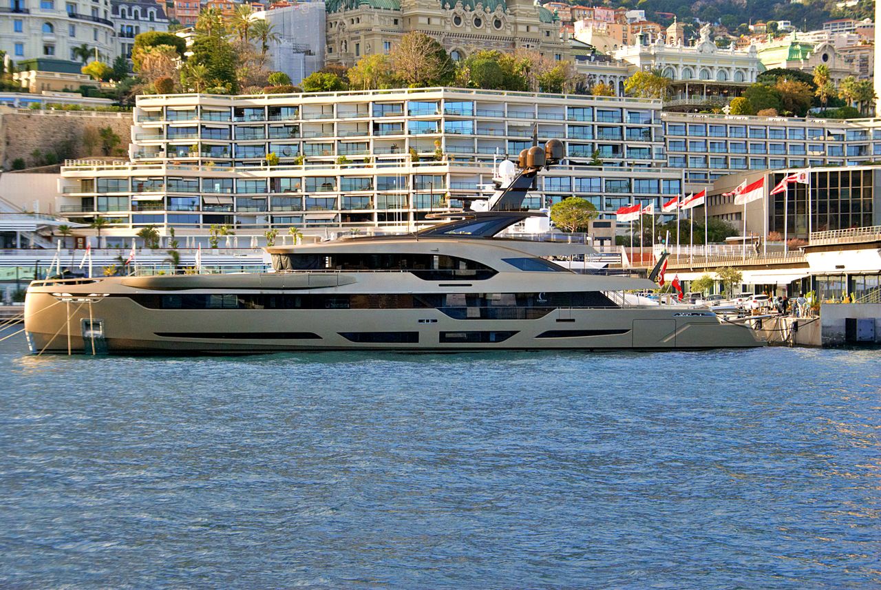 services-03 A luxury yacht moored at the picturesque Monaco harbor with modern waterfront architecture.